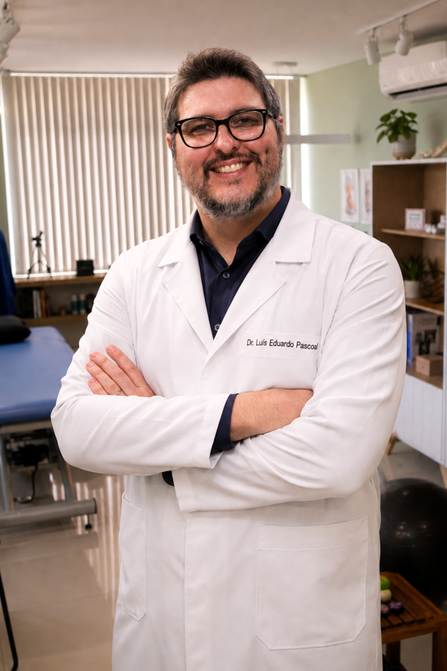 Dr. Luís Eduardo Pascoal, fisioterapeuta e osteopata da EARFF, retrato profissional de jaleco branco, óculos, braços cruzados, sorrindo, consultório clínico com maca de fisioterapia ao fundo, luz natural suave, fotografia corporativa realista